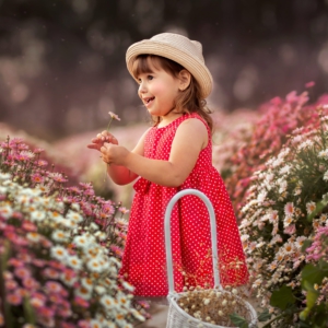 ילדה בשמלה אדומה מחייכת ומחזיקה בפרח